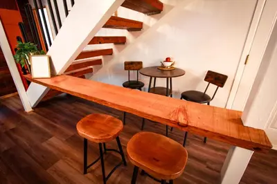 a wooden counter with stools and a table in a room at In the Pines Romantic Big Bear Forest Cabin in Fawnskin