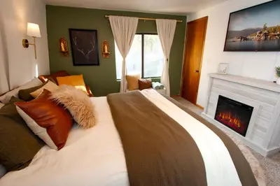 a bedroom with a large bed and a fireplace at In the Pines Romantic Big Bear Forest Cabin in Fawnskin
