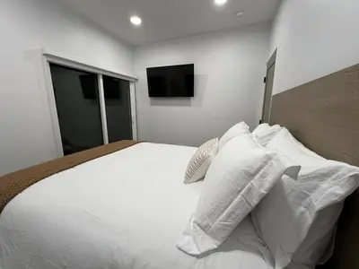 a bedroom with a white bed with pillows and a television at Castaway Cay near Disney with Hot Tub and Fire Pit in Anaheim