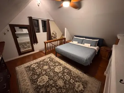 a bedroom with a bed and a mirror and a rug at Lakeview Location Hot tub Tesla Charger tree house in Big Bear Lake