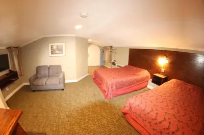 a hotel room with two beds and a chair at Santa Cruz Inn in Riverside