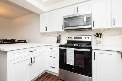 a kitchen with white cabinets and a black stove and microwave at Cozy 2BR Near Disneyland and Convention Center in Anaheim