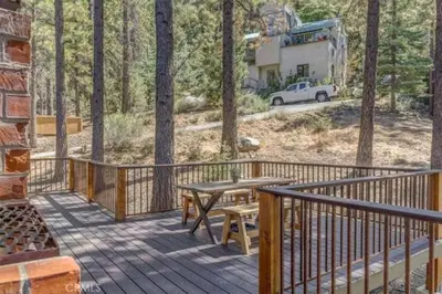 a deck with a picnic table and a truck in the woods at Pet Friendly 3BR Pine Mountain Club Cabin with King Bed and Pool Access in Pine Mountain Club