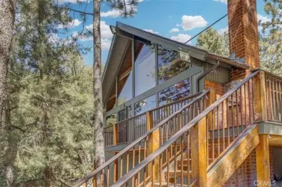 a house with a wrap around deck in the woods at Pet Friendly 3BR Pine Mountain Club Cabin with King Bed and Pool Access in Pine Mountain Club