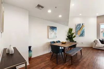 a living room with a wooden table and chairs at The Zenith Penthouse - Ocean Panoramas & Salt Air in Los Angeles