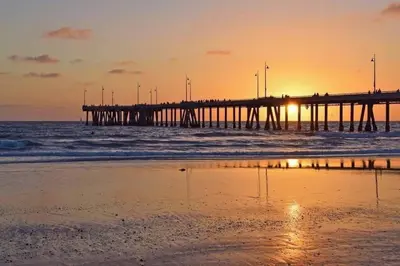 a pier in the ocean at sunset with a beach at The Zenith Penthouse - Ocean Panoramas & Salt Air in Los Angeles