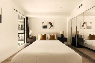 a white bedroom with a large bed and two windows at The Velvet Coast - Grand 3BR Artistic Haven in Los Angeles