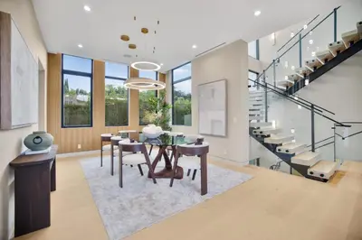 a dining room with a table and chairs and a staircase at Amestoy Modern in Los Angeles