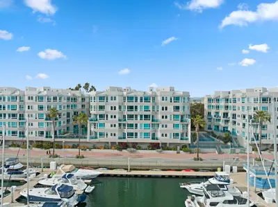 a large apartment building with boats docked in a marina at Ocean's Edge 2BR Penthouse - Infinite Blue Views in Los Angeles