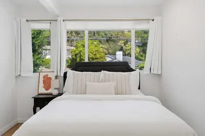 a white bedroom with a large bed and a window at Beverly Hills Canyon Estate by Colby & Conrad in Los Angeles