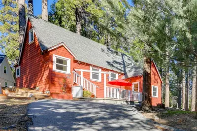 a red house with a driveway in the forest at Walk to Lake Arrowhead Village Bright Gem with Deck in Lake Arrowhead