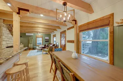a kitchen and living room with a large wooden table at 1 Mi to Lake Arrowhead! All-Season Family Getaway in Lake Arrowhead
