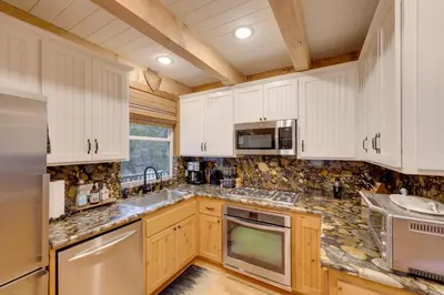 a kitchen with white cabinets and marble counter tops at 1 Mi to Lake Arrowhead! All-Season Family Getaway in Lake Arrowhead