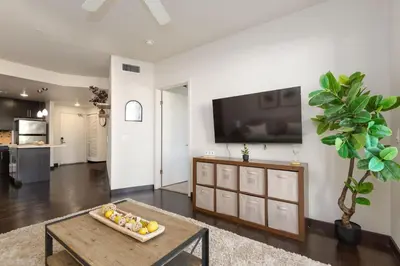 a living room with a table and a tv on a wall at West Hollywood Chic Apartment in Los Angeles