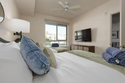a bedroom with two beds and a flat screen tv at West Hollywood Chic Apartment in Los Angeles