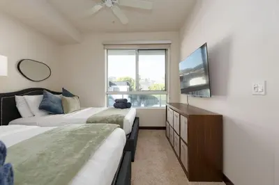 a bedroom with two beds and a flat screen tv at West Hollywood Chic Apartment in Los Angeles