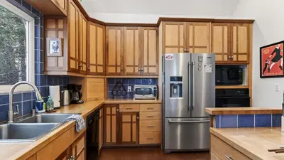 a kitchen with wooden cabinets and a stainless steel refrigerator at Holiday Lake Cabin by AvantStay Large Deck Cozy Fireplace Near Arrowhead Village in Lake Arrowhead