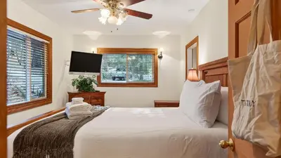 a bedroom with a bed and a flat screen tv at Holiday Lake Cabin by AvantStay Large Deck Cozy Fireplace Near Arrowhead Village in Lake Arrowhead