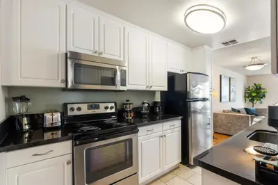 a kitchen with white cabinets and stainless steel appliances at Golden Hour Glow - Stunning 3BR Overlooking the Marina in Los Angeles