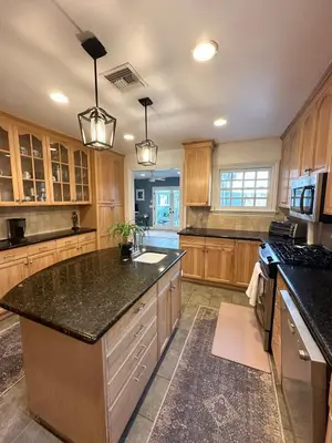 a large kitchen with wooden cabinets and a black counter top at Altadena Retreat Near Rose Bowl and Pasadena in Altadena