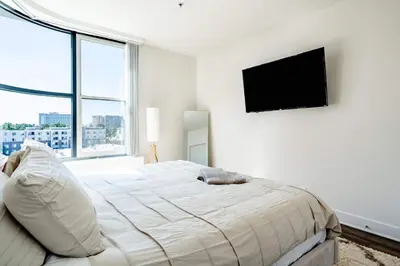 a white bedroom with a bed and a flat screen tv at Sleek Marina Den, Central, Gym, Pool, King Bed in Los Angeles