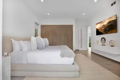 a white bedroom with a large white bed and a wall at Colgate Vantage in Los Angeles