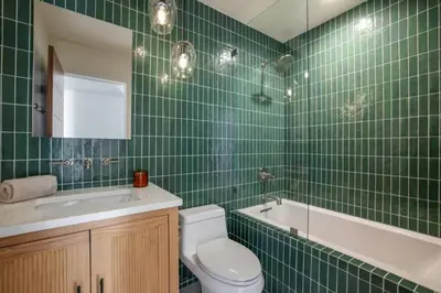 a green tiled bathroom with a toilet and a sink at Pacific Breeze - Modern Venice Beach Home in Los Angeles