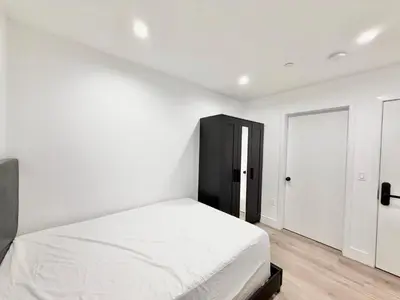 a white bedroom with a bed and a black cabinet at 1622 Palm Terrace in Los Angeles