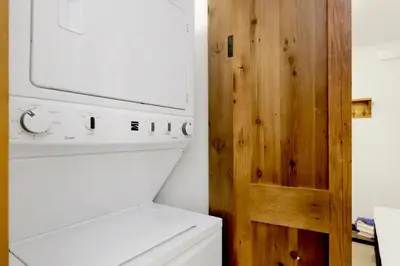 a kitchen with a washer and dryer next to a wooden door at Ursa Major Lodge | Walk to Lake & Village | Pet Friendly Retreat in Big Bear Lake
