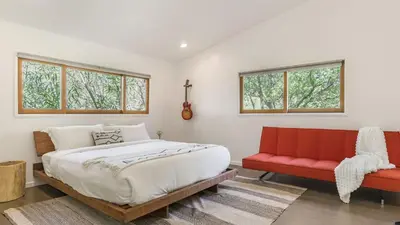 a bedroom with a bed and a red couch at The Malibu Ranch Retreat by AvanStay Malibu Escape • Valley Views Near Zuma The Ranch Malibu in Malibu