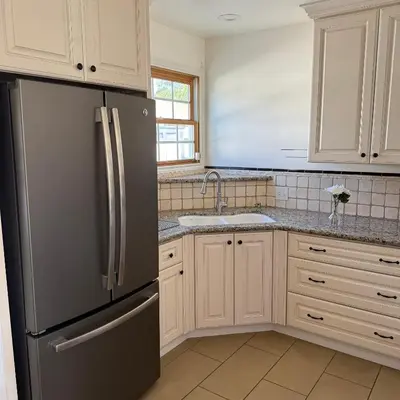 a kitchen with a stainless steel refrigerator and white cabinets at Cozy House in Hewitt