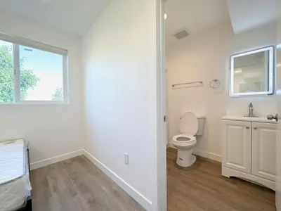 a white bathroom with a toilet and a window at Eiven Homestay in Los Angeles