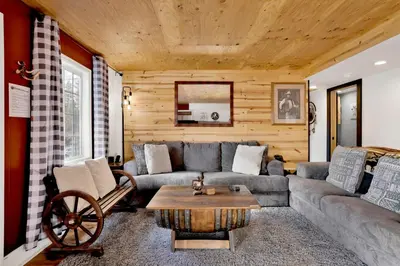 a living room with a couch and a table at Highland Hideaway at Big Bear | Cozy Cabin w/ Private Hot Tub in Big Bear Lake