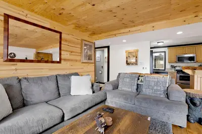a living room with a couch and a table at Highland Hideaway at Big Bear | Cozy Cabin w/ Private Hot Tub in Big Bear Lake