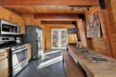 a kitchen with wooden walls and a large wooden table at The Cave at Big Bear Lake - Adorable Mountain Retreat w/ Hot Tub in Big Bear Lake