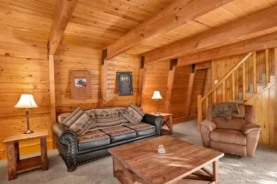 a living room with a couch and a table in a cabin at The Cave at Big Bear Lake - Adorable Mountain Retreat w/ Hot Tub in Big Bear Lake
