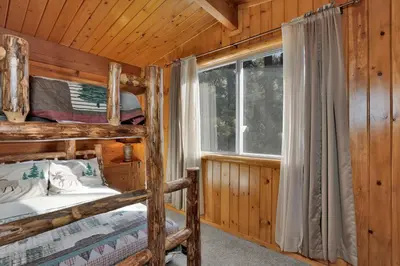 a bedroom with two bunk beds in a log cabin at The Cave at Big Bear Lake - Adorable Mountain Retreat w/ Hot Tub in Big Bear Lake