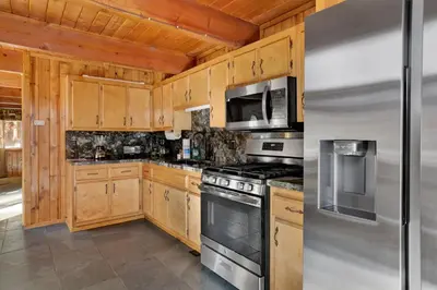 a kitchen with wooden cabinets and stainless steel appliances at The Cave at Big Bear Lake - Adorable Mountain Retreat w/ Hot Tub in Big Bear Lake