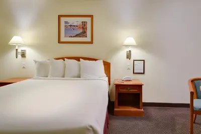 a hotel room with a large bed and a table at Vagabond Inn Hacienda Heights in Hacienda Heights