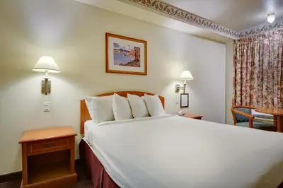 a hotel room with a large bed and a chair at Vagabond Inn Hacienda Heights in Hacienda Heights