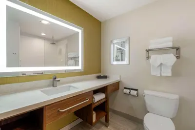 a bathroom with a sink and a mirror and a toilet at Best Western Plus Gardena-Los Angeles Inn & Suites in Gardena