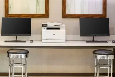a desk with two monitors and a printer and two bar stools at Best Western Plus Gardena-Los Angeles Inn & Suites in Gardena