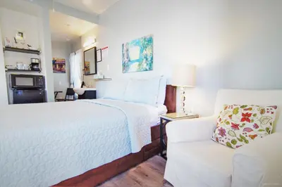a bedroom with a white bed and a white chair at Hotel Royal in Long Beach