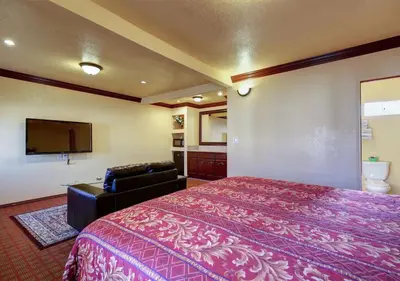 a hotel room with a bed and a flat screen tv at Welcome Inn in Inglewood