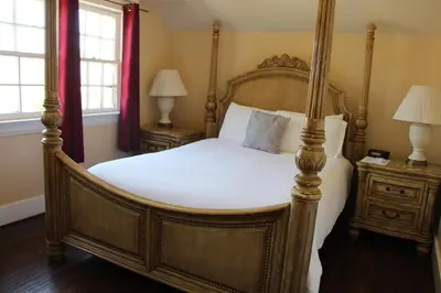 a bedroom with a four poster bed and two lamps at Glen Tavern Inn in Santa Paula