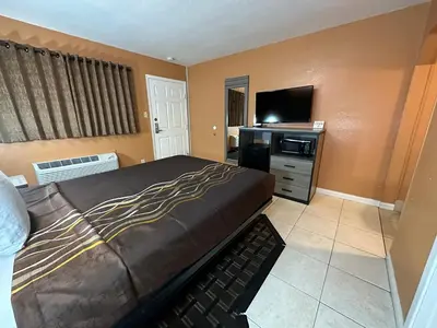 a bedroom with a bed and a flat screen tv at New Corral Motel in Victorville