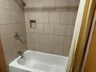 a white bath tub in a bathroom with a shower at New Corral Motel in Victorville