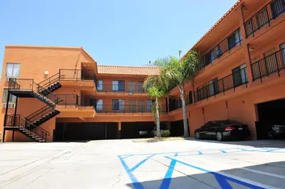 a parking lot in front of a building with a palm tree at Motel 6-Inglewood, CA in Inglewood