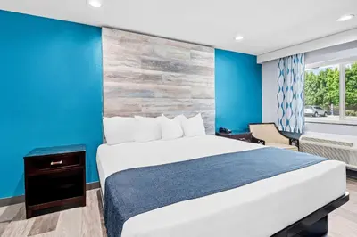 a bedroom with a bed and a blue wall at SureStay Hotel by Best Western Buena Park Anaheim in Buena Park