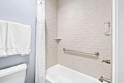 a bathroom with a white toilet and a shower at SureStay Hotel by Best Western Buena Park Anaheim in Buena Park